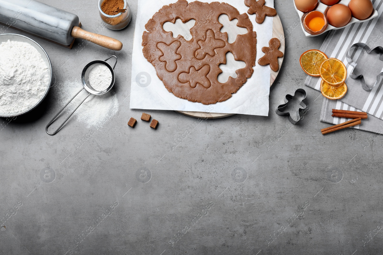 Photo of Flat lay composition with homemade gingerbread man cookies on grey table, space for text