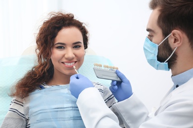 Photo of Dentist matching patient's teeth color with palette in office