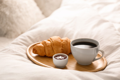 Photo of Delicious morning coffee and croissant on bed