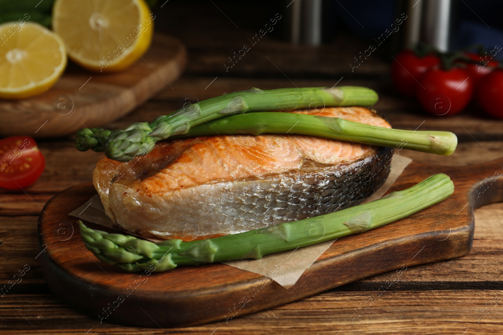 Photo of Tasty salmon steak served with asparagus on wooden table