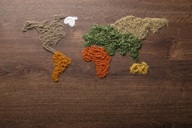 World map of different spices on wooden table, flat lay