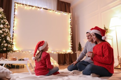 Photo of Family near video projector screen at home. Christmas time