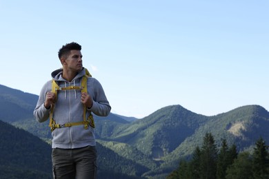 Tourist with backpack in mountains, space for text