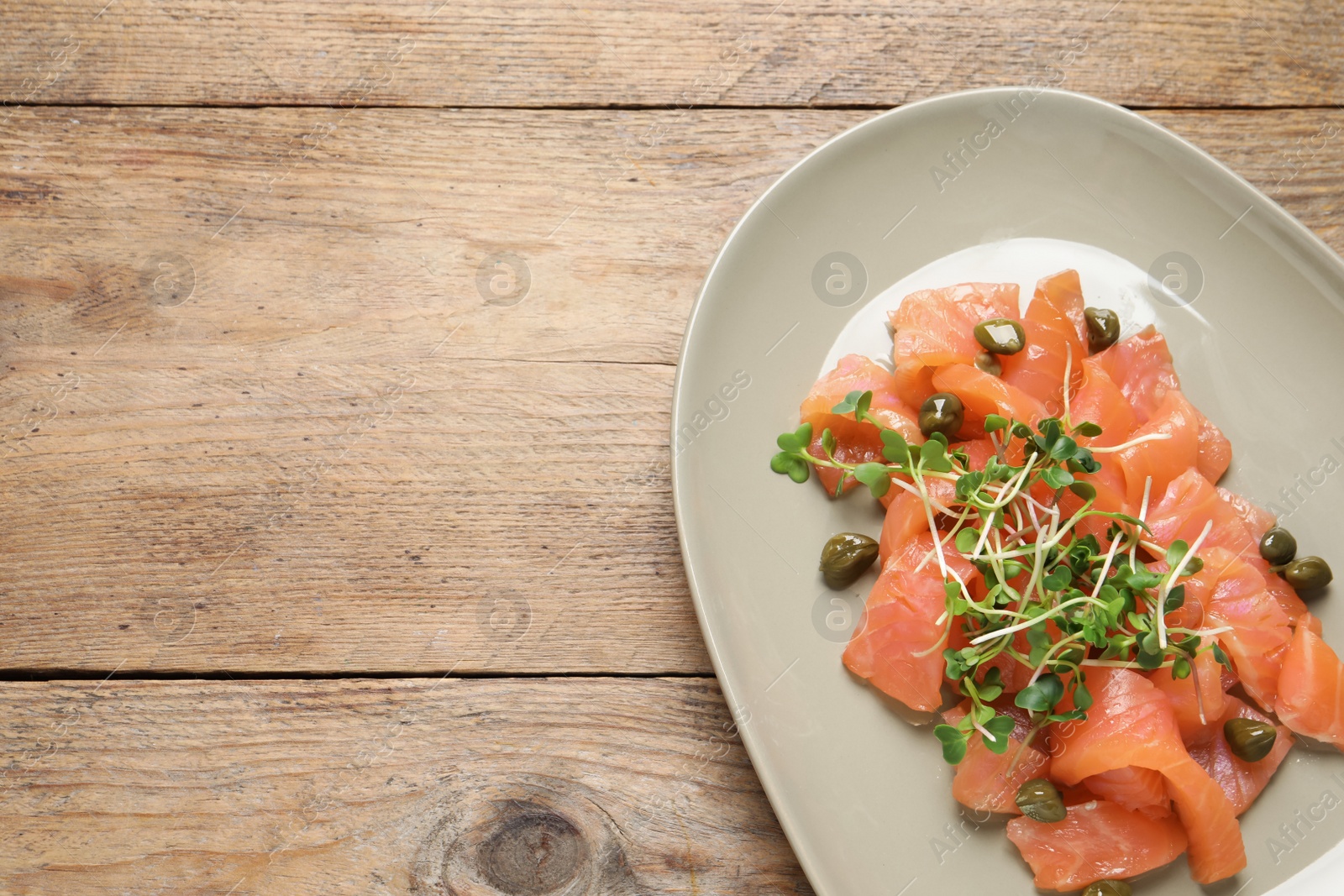 Photo of Delicious salmon carpaccio served on wooden table, top view. Space for text