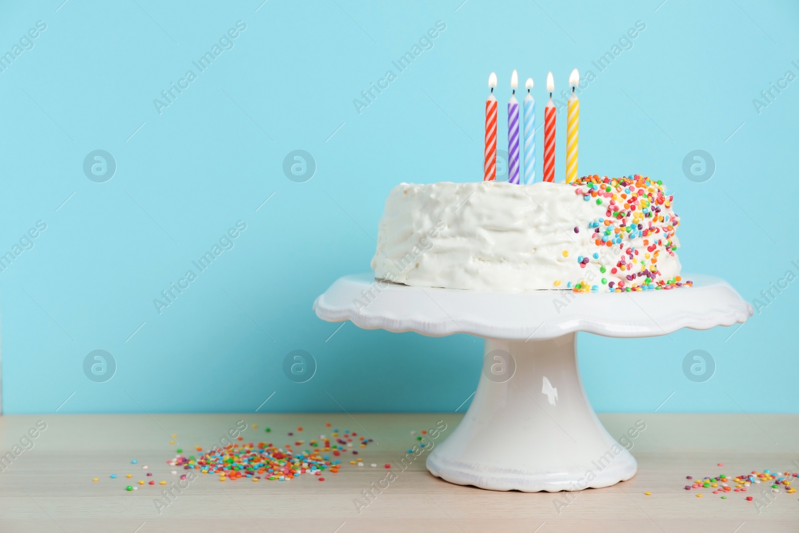 Photo of Birthday cake with candles on table against color background