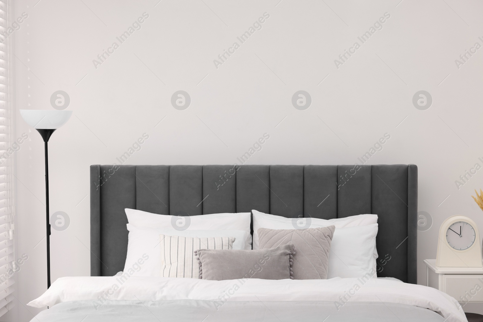 Photo of Large bed and lamp in stylish bedroom. Interior design