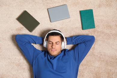 Man listening to audiobook on floor, top view