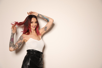 Photo of Beautiful woman with tattoos on arms against light background. Space for text