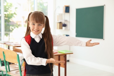 Photo of Little girl in classroom. Stylish school uniform