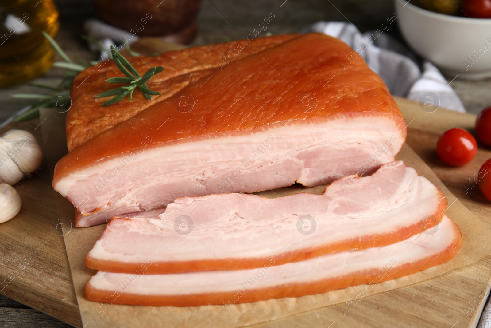 Photo of Delicious smoked bacon with rosemary on wooden board, closeup