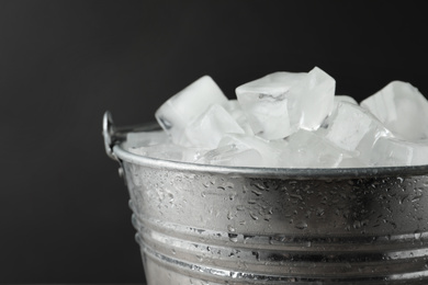 Metal bucket with ice cubes on dark background, closeup