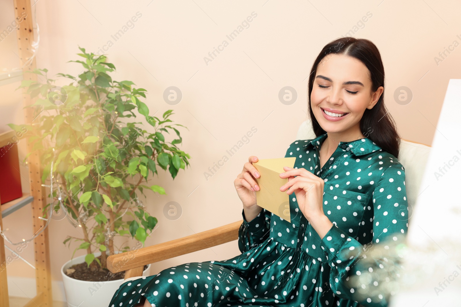 Photo of Happy woman holding greeting card in living room