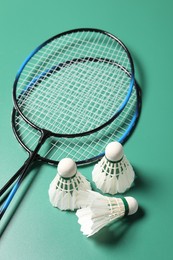 Photo of Feather badminton shuttlecocks and rackets on green background