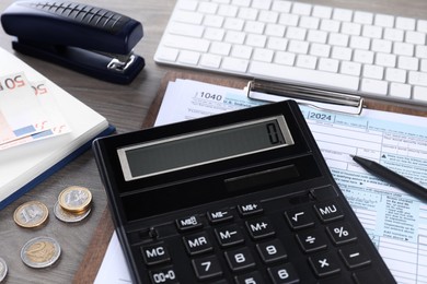 Photo of Tax accounting. Calculator, document, coins, keyboard and stationery on wooden table, closeup