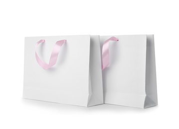 Photo of Paper shopping bags with ribbon handles on white background. Mockup for design