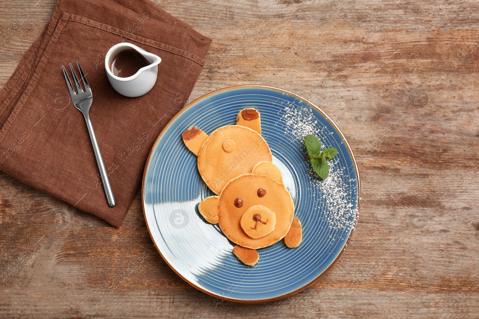 Photo of Flat lay composition with pancakes in form of bear on wooden background. Creative breakfast ideas for kids