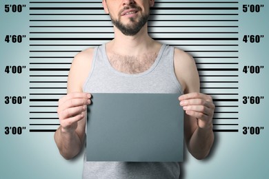 Image of Criminal mugshot. Arrested man with blank card against height chart, closeup