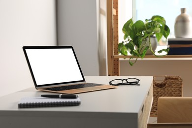 Photo of Workplace with modern laptop and glasses on white table. Mockup for design