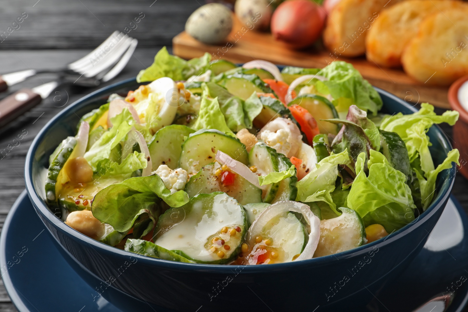 Photo of Bowl of delicious cucumber salad served on black table, closeup