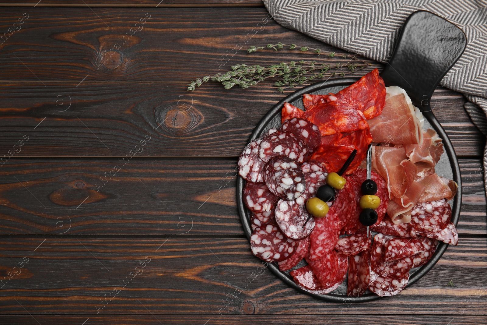 Photo of Tasty prosciutto and other delicacies served on wooden table, flat lay. Space for text