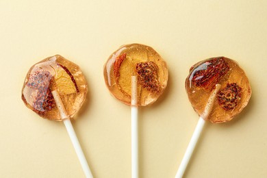 Sweet colorful lollipops with berries on beige background, flat lay