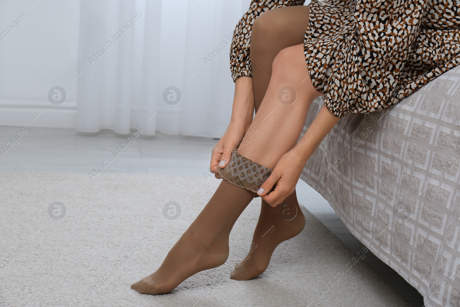 Photo of Woman wearing compression tights on bed indoors, closeup