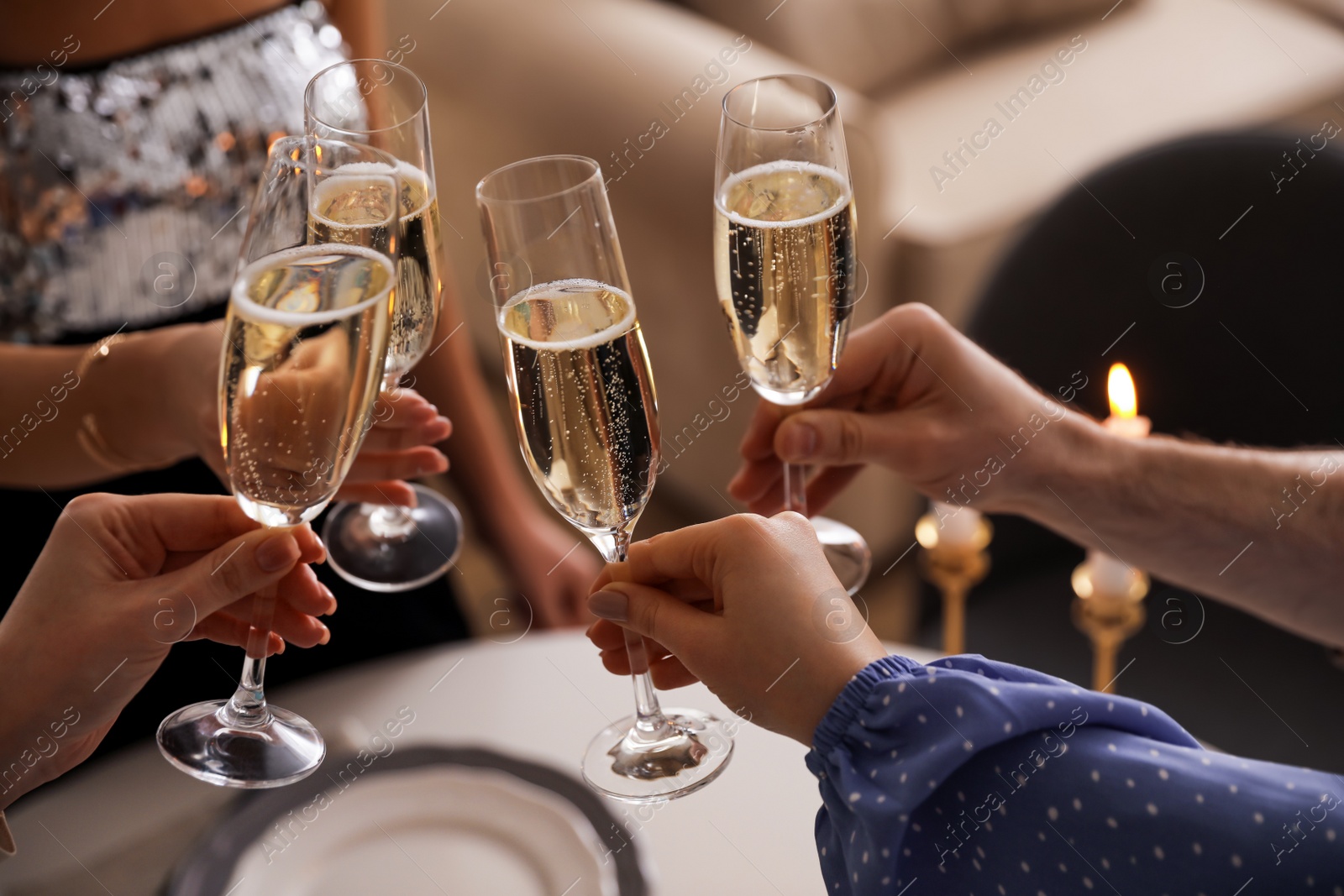 Photo of People clinking glasses with champagne at home, closeup