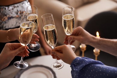 People clinking glasses with champagne at home, closeup