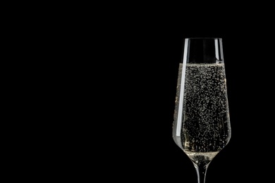 Photo of Glass of champagne on black background, space for text