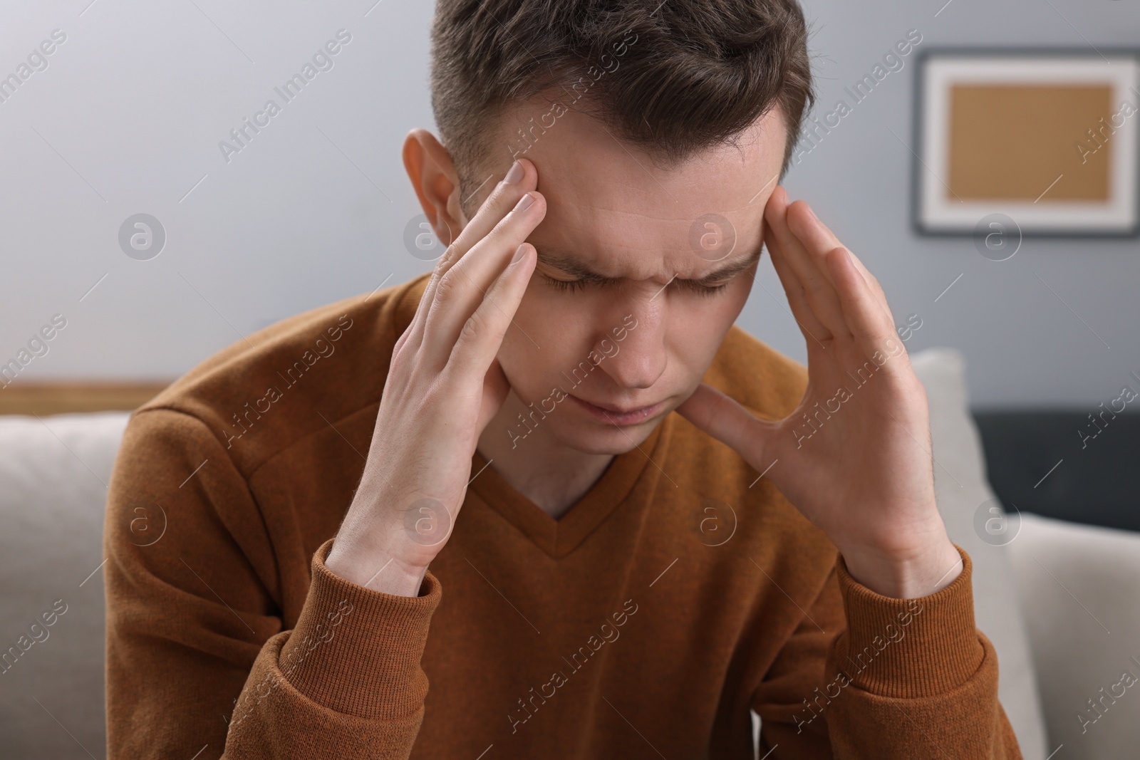 Photo of Sad man suffering from headache on sofa indoors