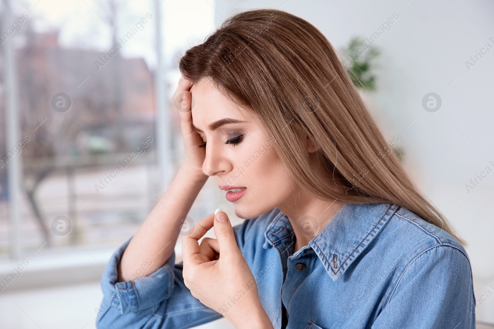 Photo of Young woman taking pill indoors