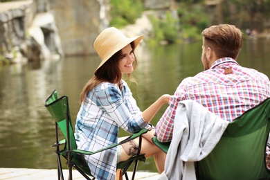 Photo of Young couple resting on pier near lake. Camping season