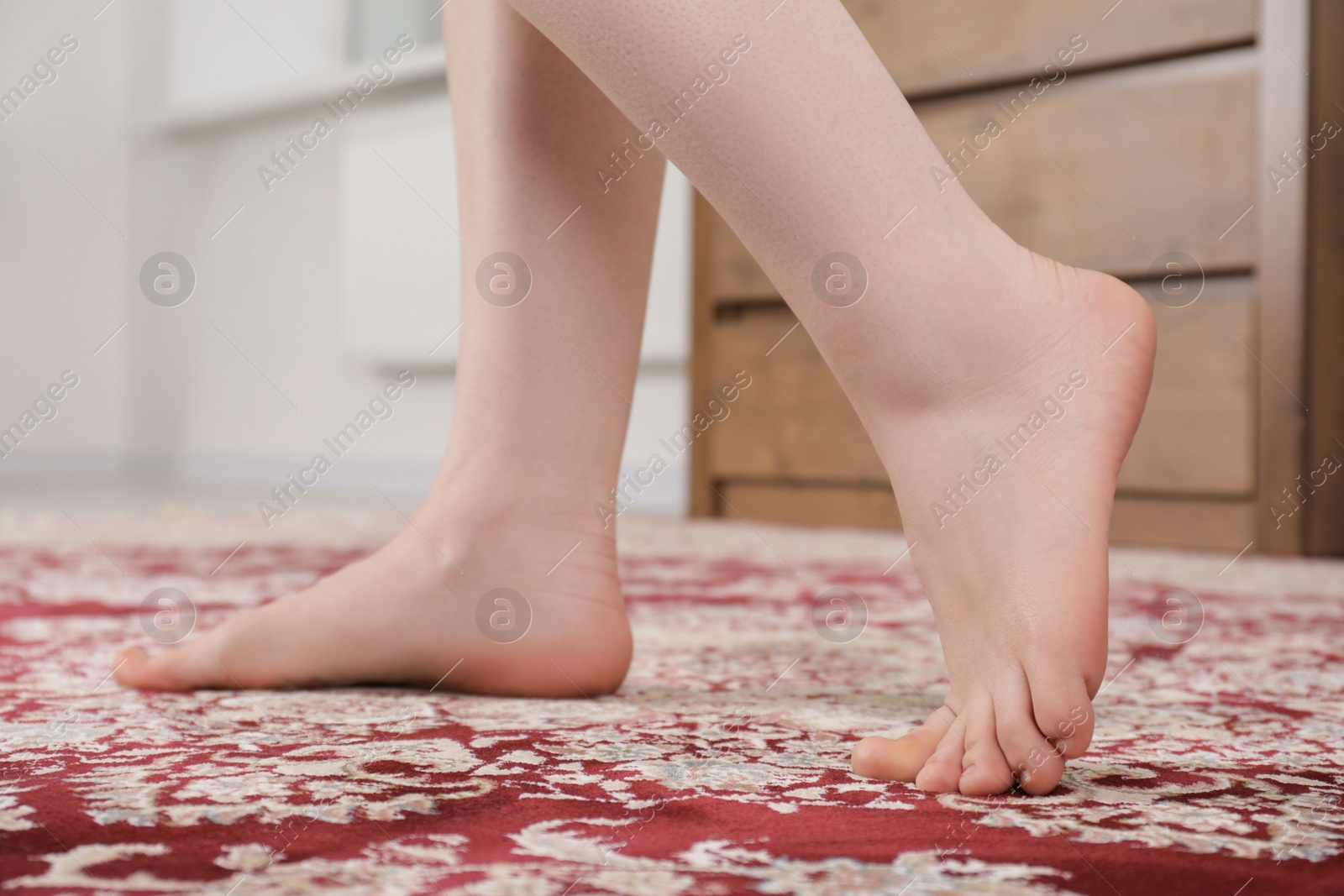 Photo of Woman standing on carpet with pattern at home, closeup