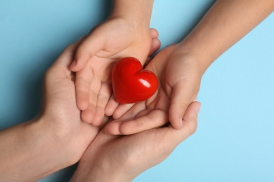 Photo of Closeup of woman and child holding heart on blue background, top view. Donation concept