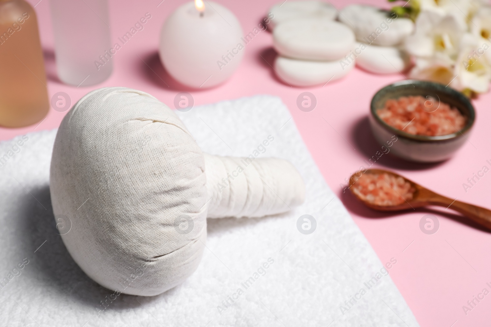 Photo of Herbal massage bag and other spa products on pink background, closeup. Space for text