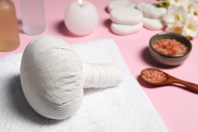 Photo of Herbal massage bag and other spa products on pink background, closeup. Space for text