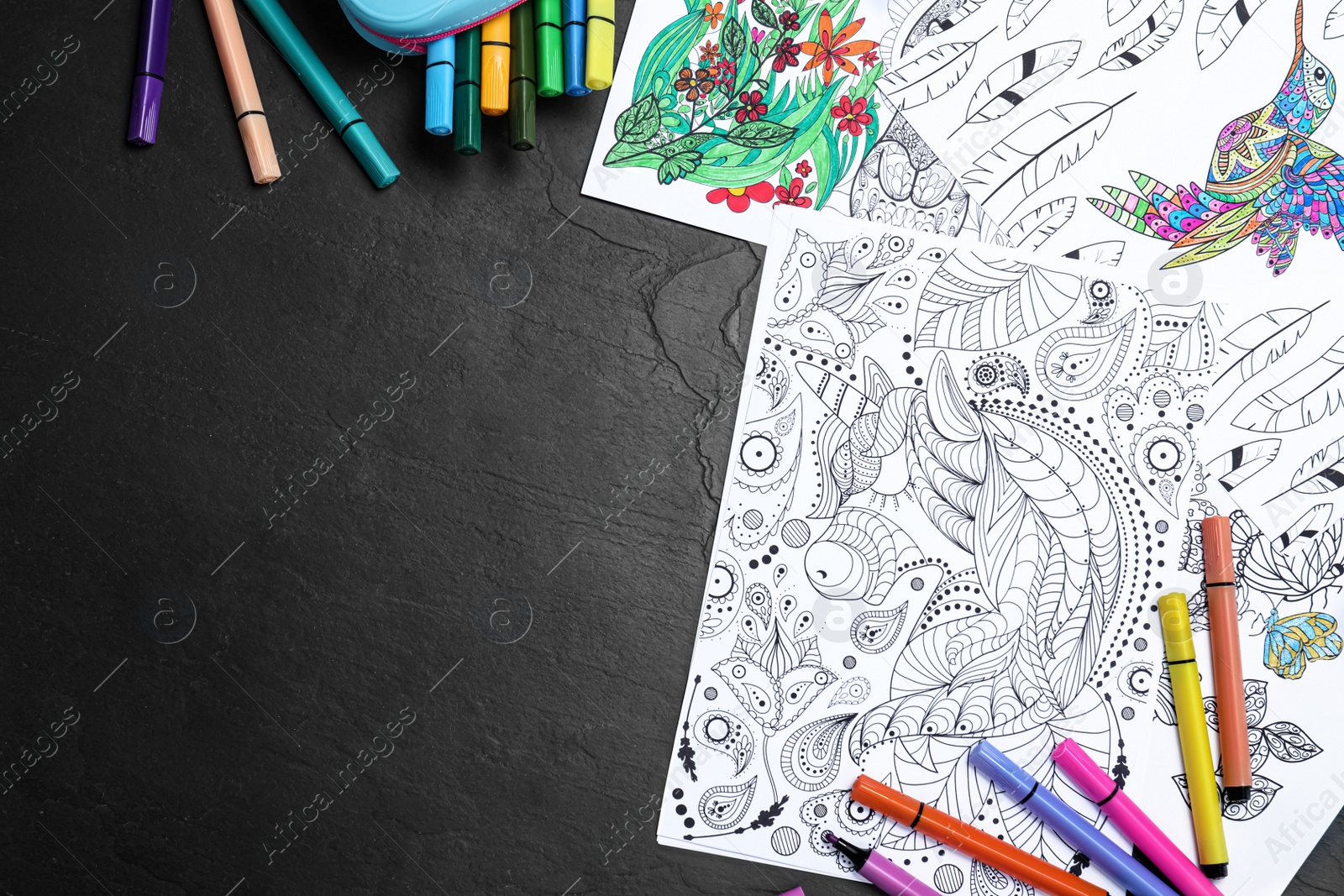 Photo of Antistress coloring pages and felt tip pens on black table, flat lay. Space for text