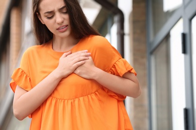 Photo of Young woman having chest pain outdoors. Heart attack