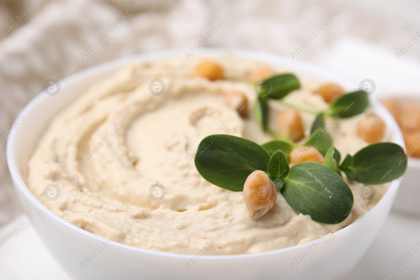 Photo of Bowl of delicious hummus with chickpeas, closeup