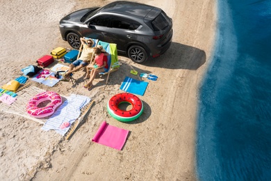 Image of Family with beach accessories and car near river, aerial view. Summer trip