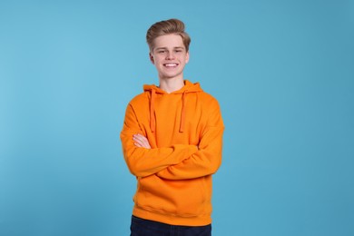 Portrait of smiling teenage boy on light blue background