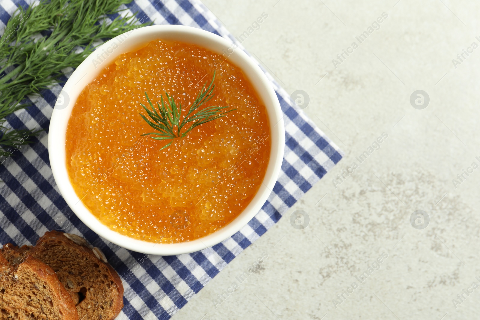 Photo of Fresh pike caviar in bowl, dill and bread on light grey table, top view. Space for text