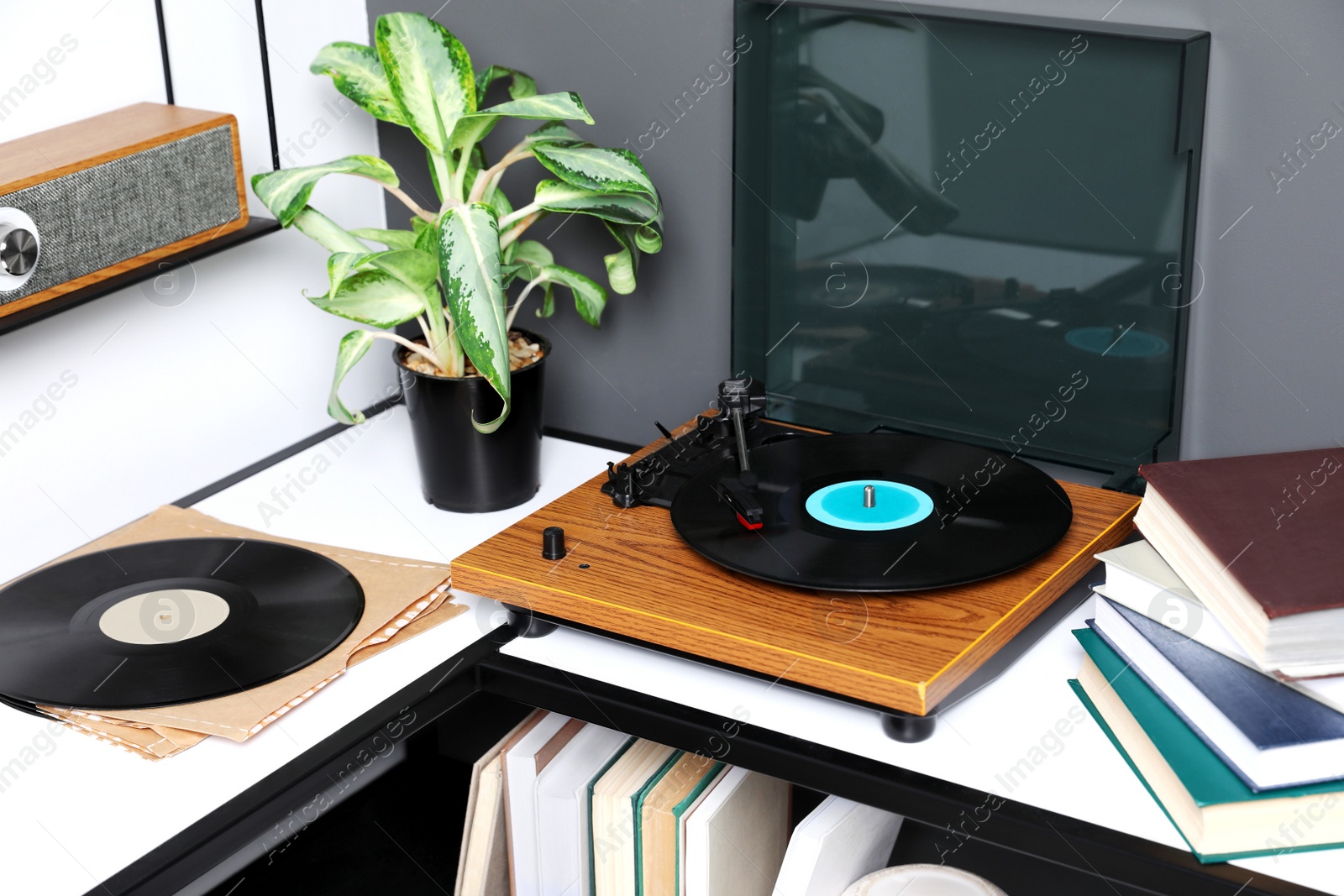 Photo of Stylish turntable with vinyl disc near grey wall in room