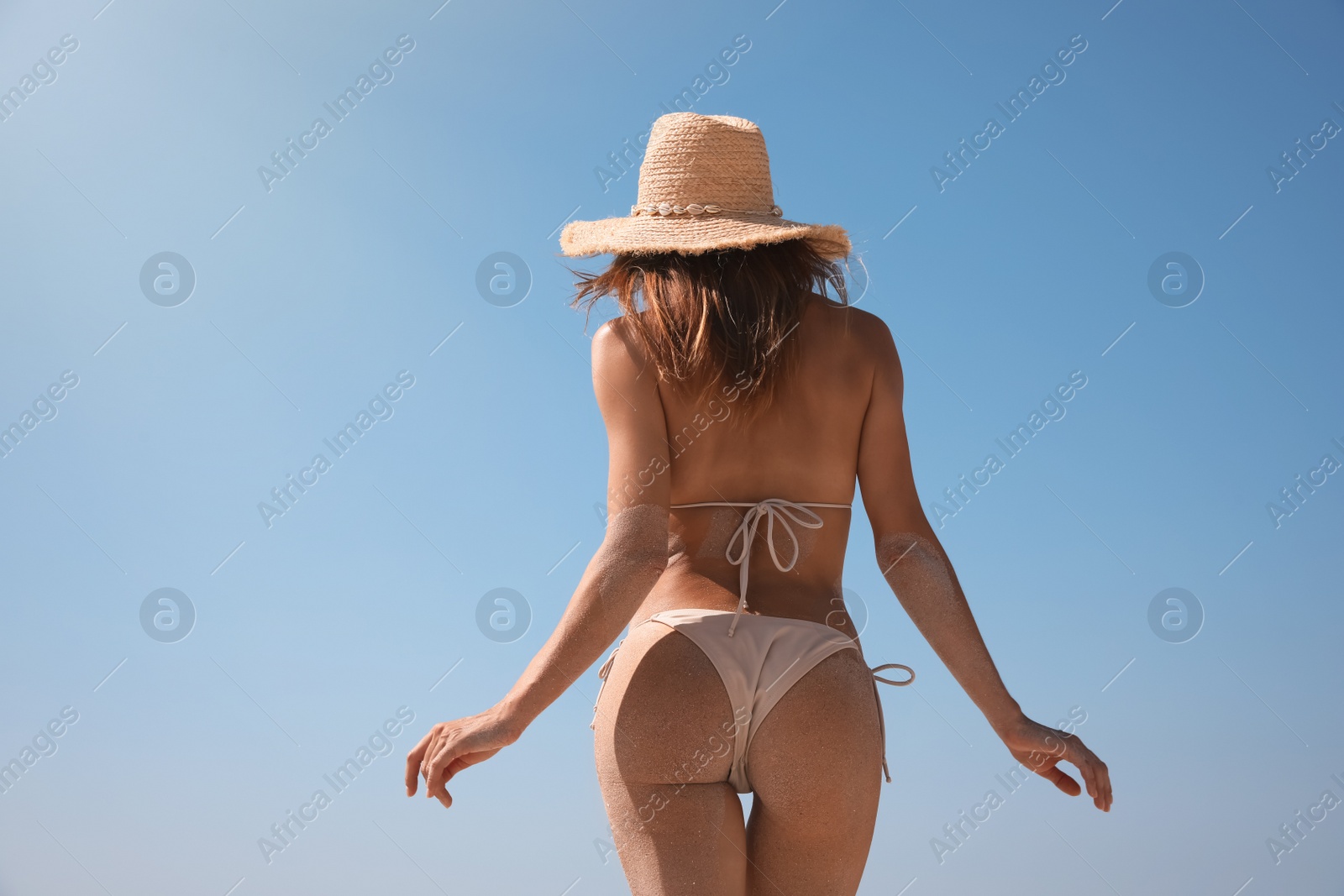 Photo of Woman with perfect body in bikini against blue sky, back view