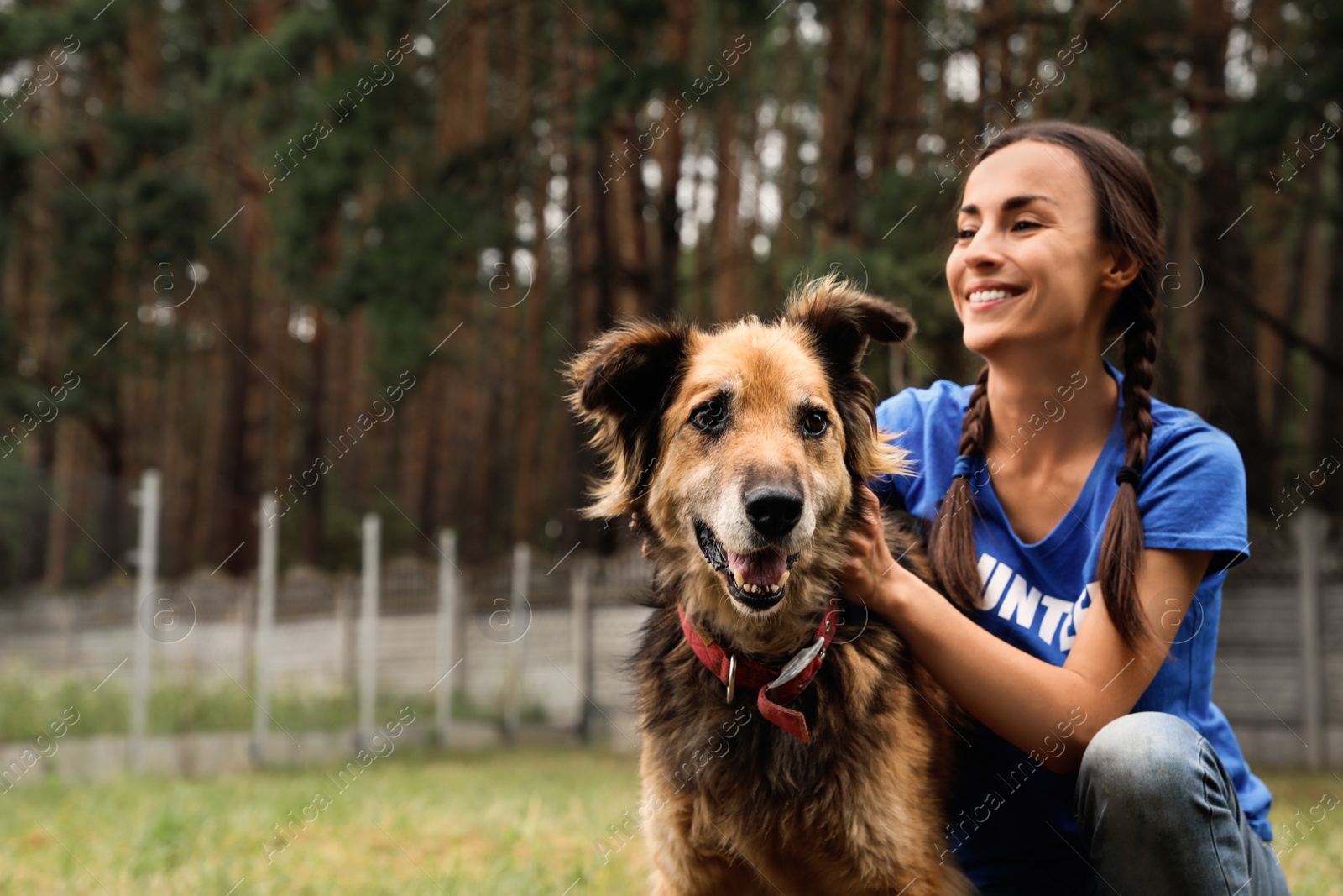 Photo of Female volunteer with homeless dog at animal shelter outdoors