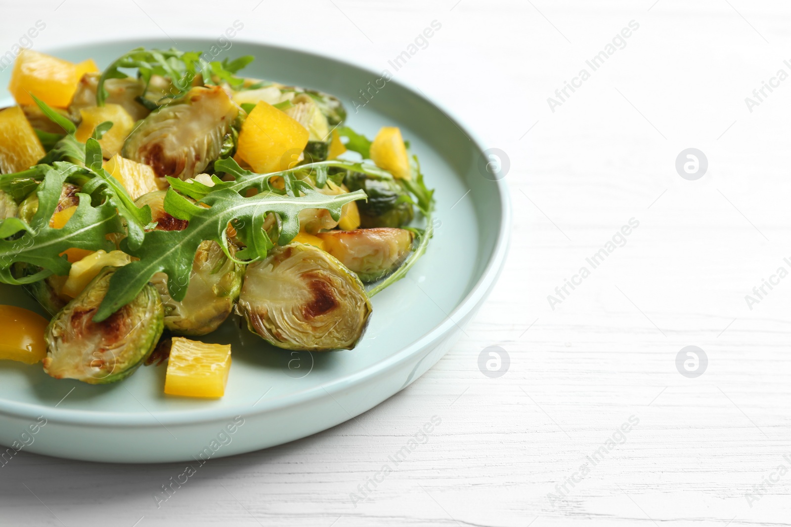 Photo of Delicious salad with roasted Brussels sprouts on white wooden table, closeup