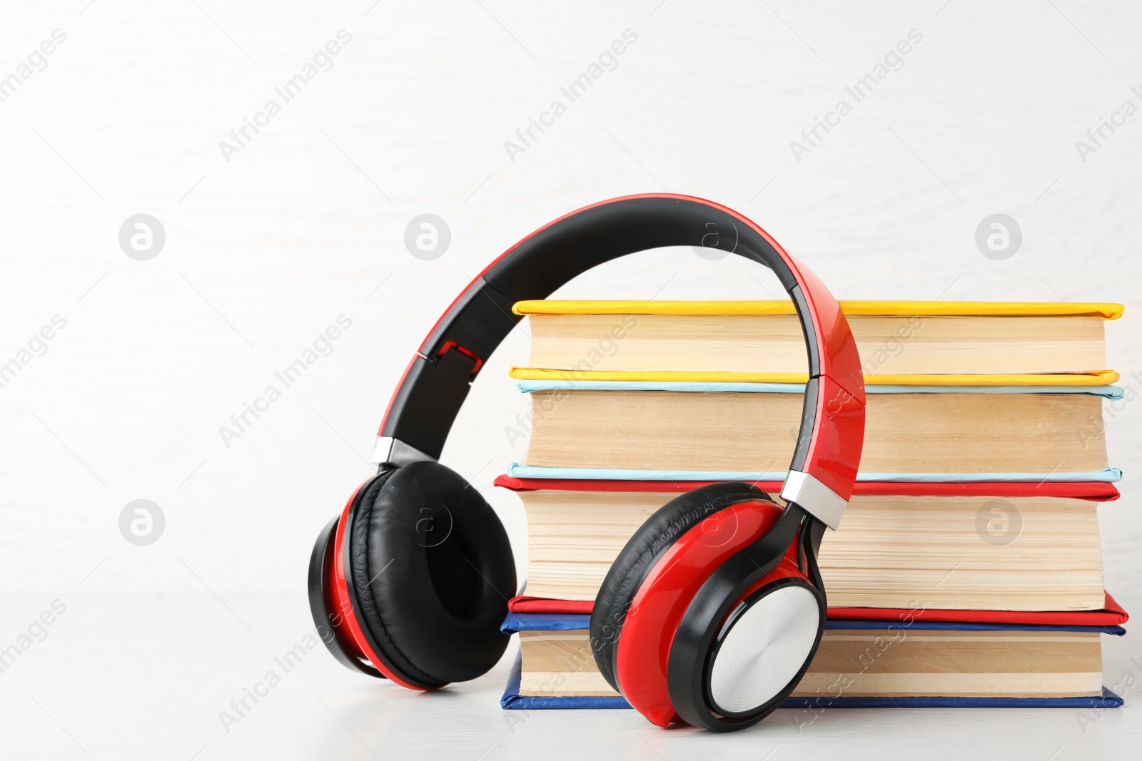 Photo of Books and modern headphones on white background. Space for text