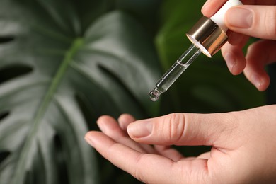 Photo of Woman applying cosmetic serum onto hand on blurred background, closeup. Space for text