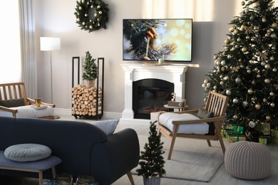 Photo of Modern TV set on light wall in room decorated for Christmas