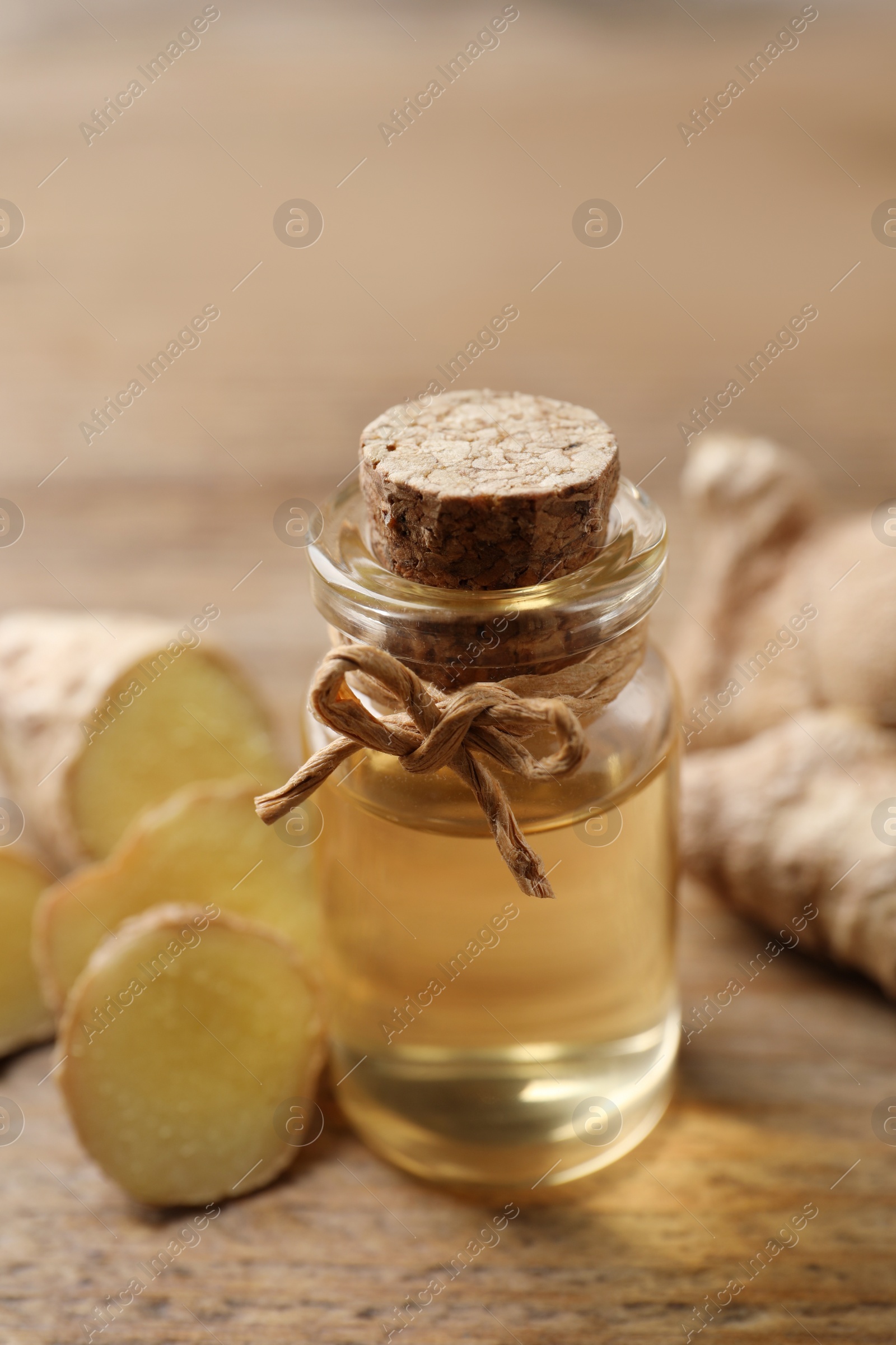 Photo of Ginger essential oil in bottle on wooden table, closeup